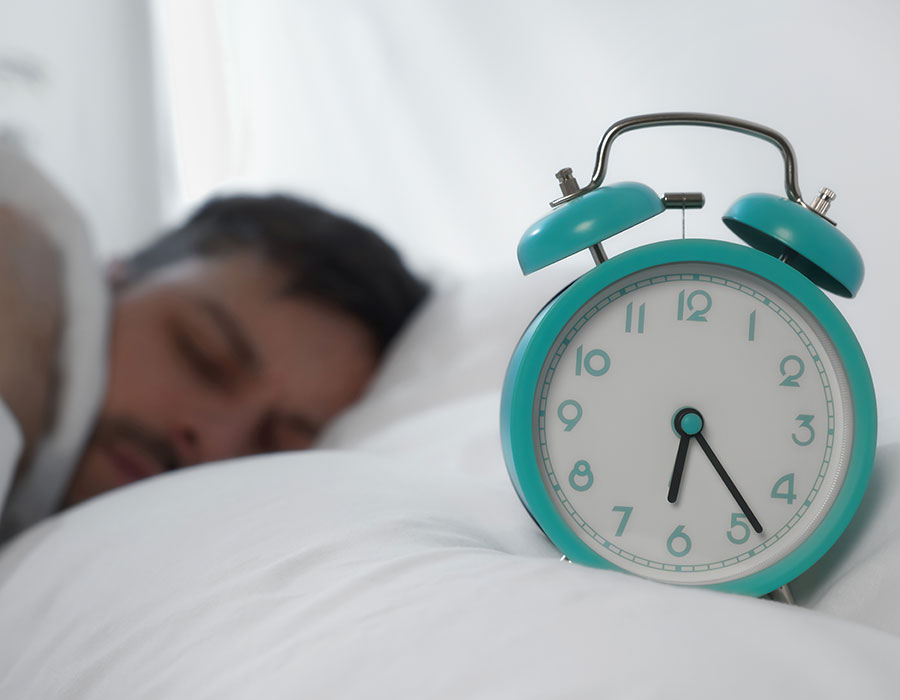 Man sleeping next to an alarm clock