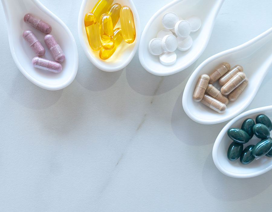 Medicine or vitamin in white spoons on white table.