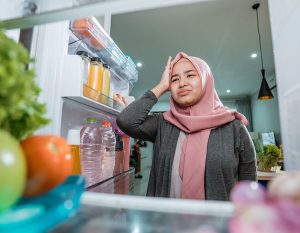 Woman while opening the fridge door deciding what to eat